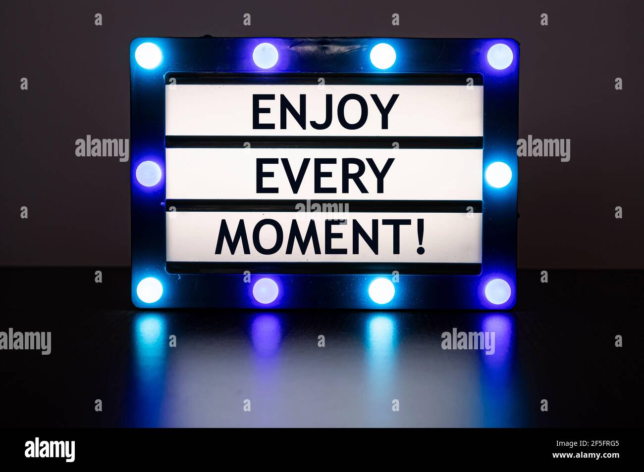 Leuchtkasten mit blauen Lichtern mit Worten - genießen Sie jeden Moment! Stockfoto