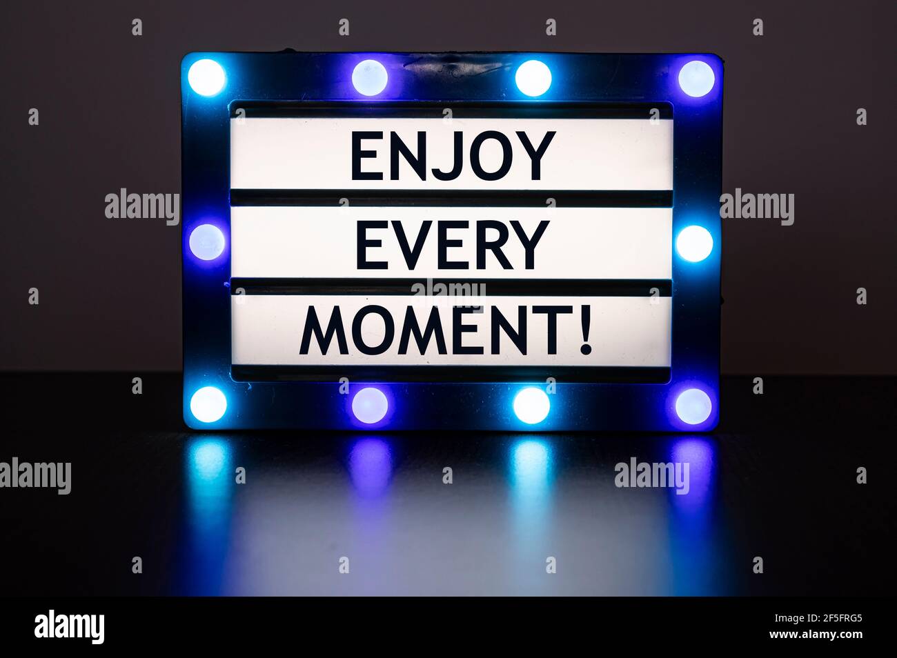 Leuchtkasten mit blauen Lichtern mit Worten - genießen Sie jeden Moment! Stockfoto