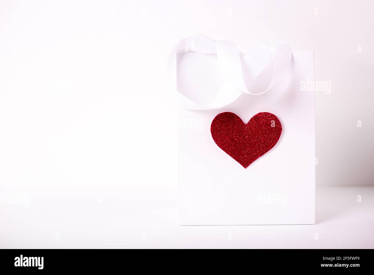 Rosen und Geschenk in Papierpackung mit rotem Herz Auf weißem Hintergrund/ Valentinstag Hintergrund Stockfoto