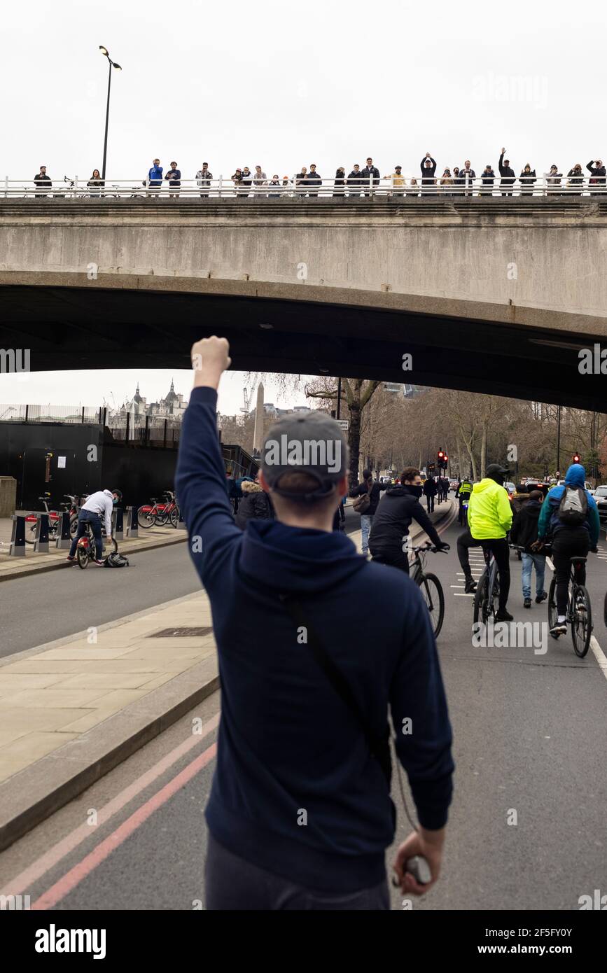 Anti-Lockdown und Anti-Covid-19-Impfprotest, London, 20. März 2021. Der Protestler hebt die Faust vor den Zuschauern auf der Brücke. Stockfoto