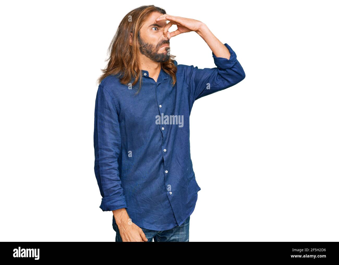 Attraktiver Mann mit langen Haaren und Bart in lässiger Kleidung, der etwas stinkendes und
