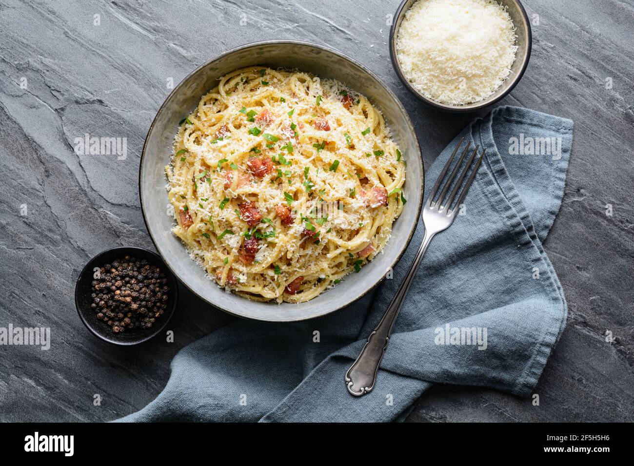 Klassische Pasta Carbonara in einer Keramikplatte, herzhaftes italienisches Gericht mit Spaghetti, Ei, gebratenem Speck, gekrönt mit geriebenem Parmesan-Käse und schwarzem pe Stockfoto