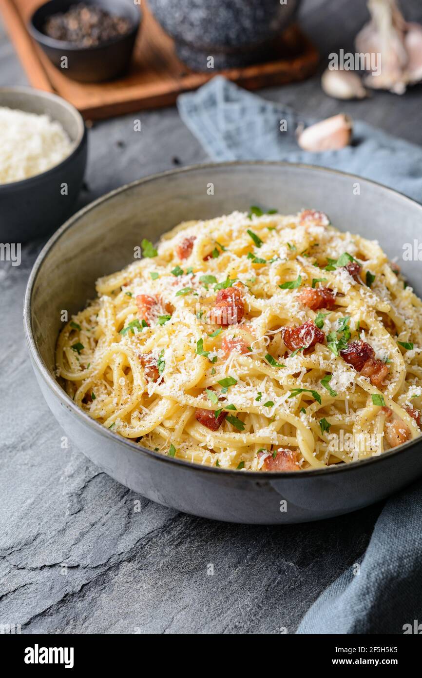 Klassische Pasta Carbonara in einer Keramikplatte, herzhaftes italienisches Gericht mit Spaghetti, Ei, gebratenem Speck, gekrönt mit geriebenem Parmesan-Käse und schwarzem pe Stockfoto