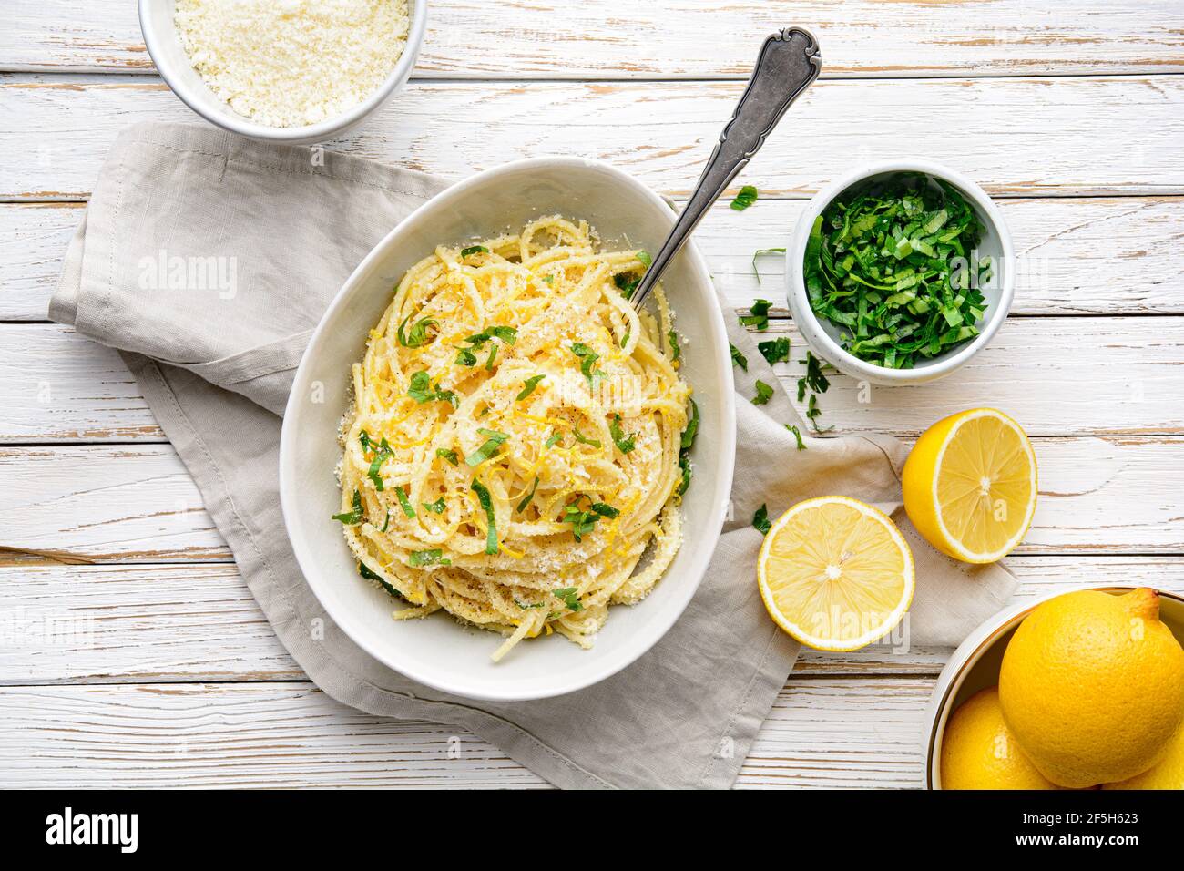 Pasta al Limone, köstliche italienische Mahlzeit, Spaghetti mit Parmesan, Butter und Zitronensauce, gekrönt mit frisch geriebener Schale und Käse auf rustikalem Holz BA Stockfoto