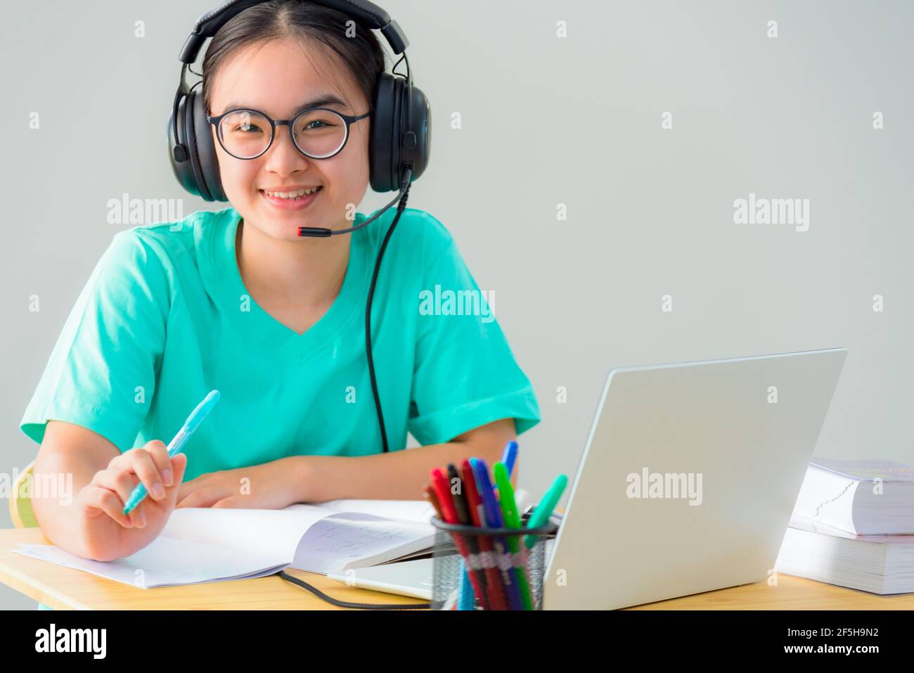 Portrait Asian junge Frau Student Brille Kopfhörer sitzen glücklich Studie Lächeln suchen online Klasse Hochschule Lernen Internet Bildung, Teenage g Stockfoto
