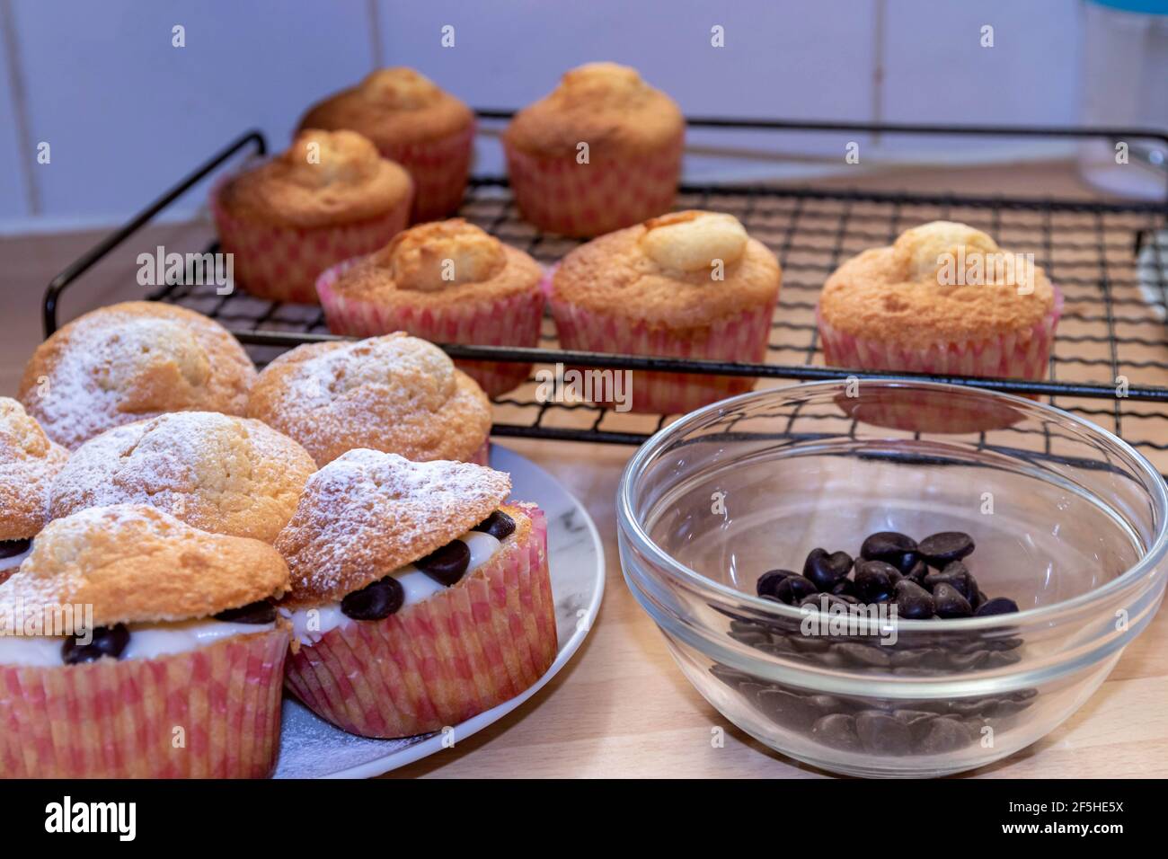 Cupcakes nach vorne mit Sahne und Schokoladenstückchen, andere im Hintergrund auf einem Kühlregal Stockfoto