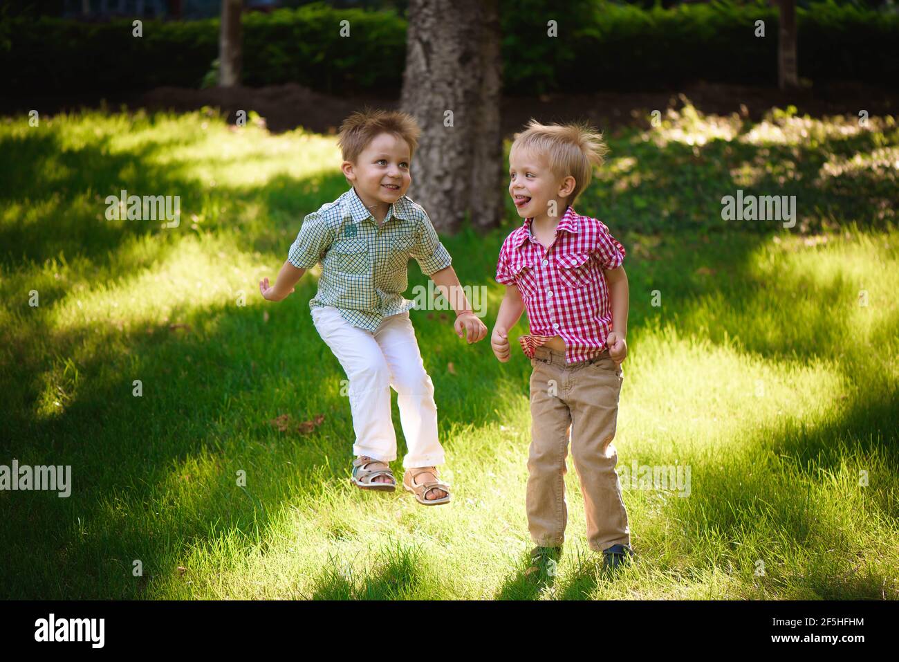 Zwei Jungen Brüder spielen und springen im Freien in einem Park. Stockfoto