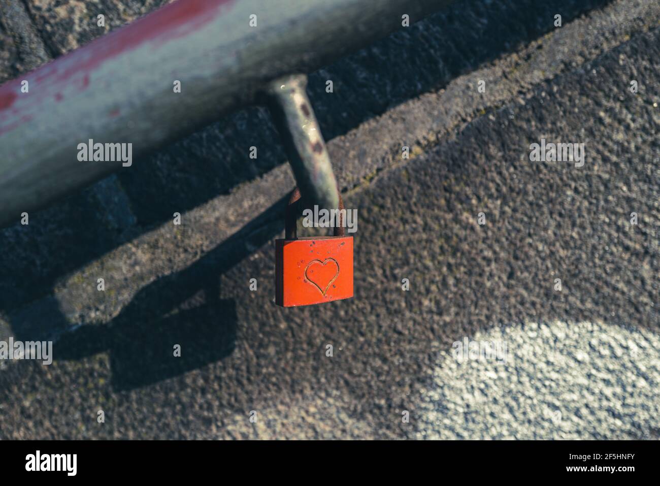 An einem hängt ein rotes Vorhängeschloss, das mit einem Herz eingraviert ist Handlauf einer Treppe Stockfoto