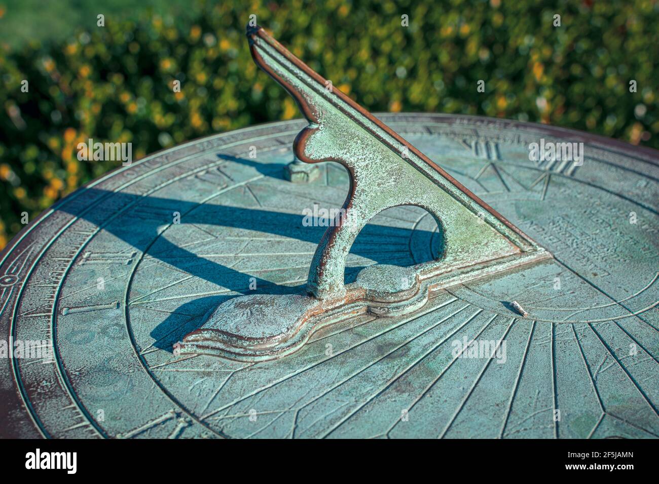 Eine vintage Sonnenuhr mit einer alternden Patina wirft einen langen Schatten, verfolgt die Bewegung der Sonne und erzählt gleichzeitig die Tageszeit. Stockfoto