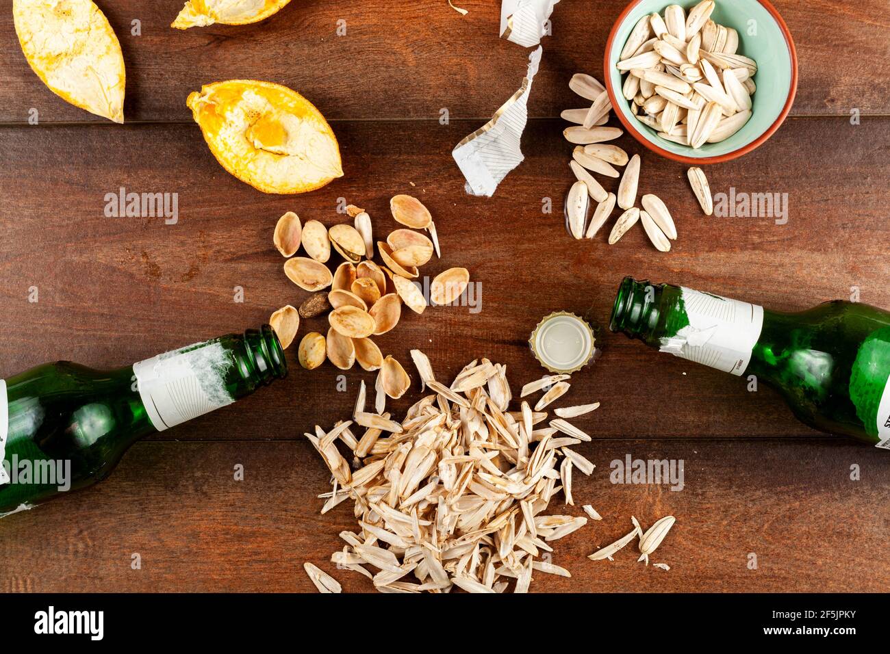 Unordentlich, chaotisch nach Party Tischansicht mit Sonnenblumenkernen, Pistazien, übrig gebliebenen Schalen und Orangenschalen sowie Bierflaschen auf dem Tisch. Qui Stockfoto