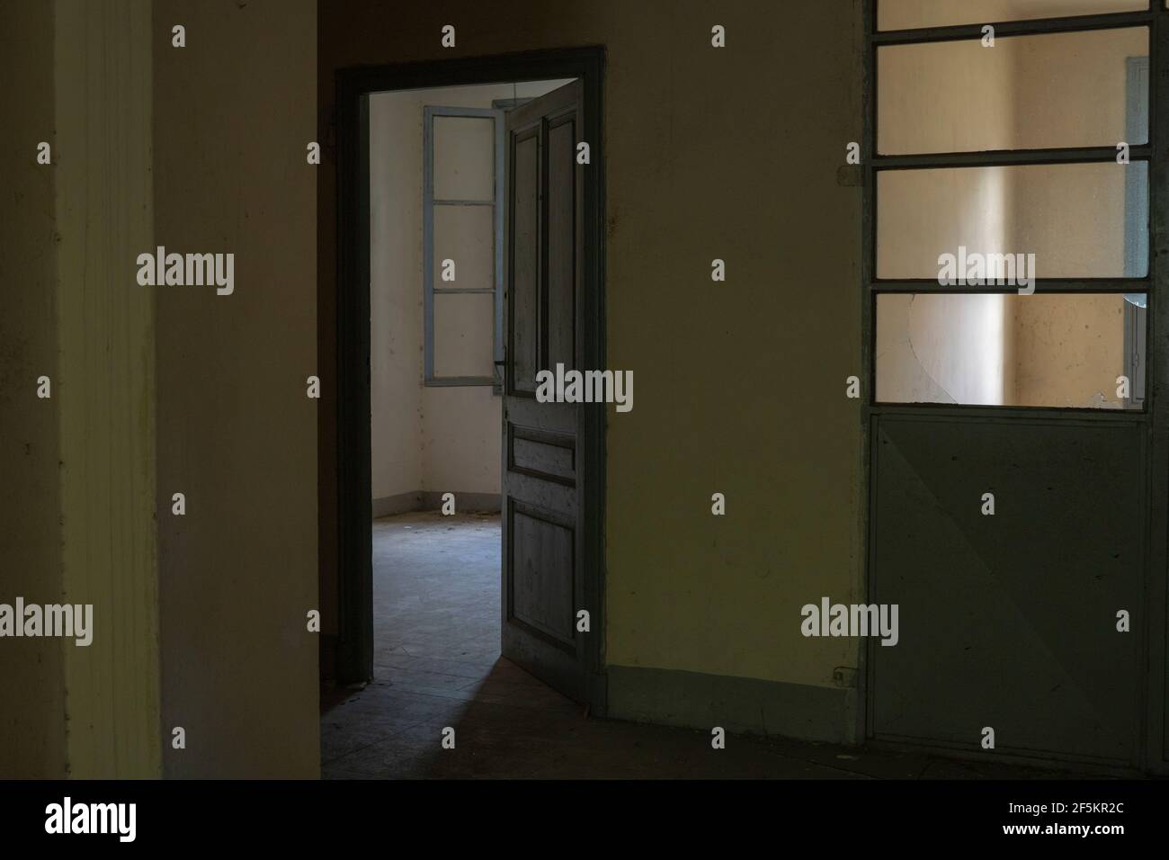 Im Inneren eines verlassenen dunklen Gebäudes kommt nur wenig Licht durch das Fenster Stockfoto