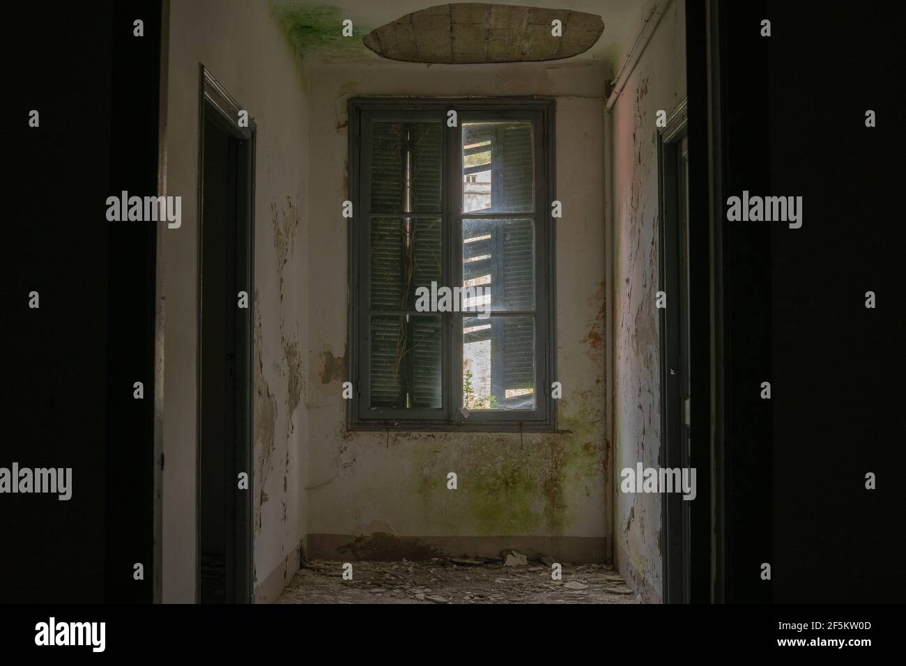 Im Inneren eines verlassenen dunklen Gebäudes kommt nur wenig Licht durch das Fenster Stockfoto