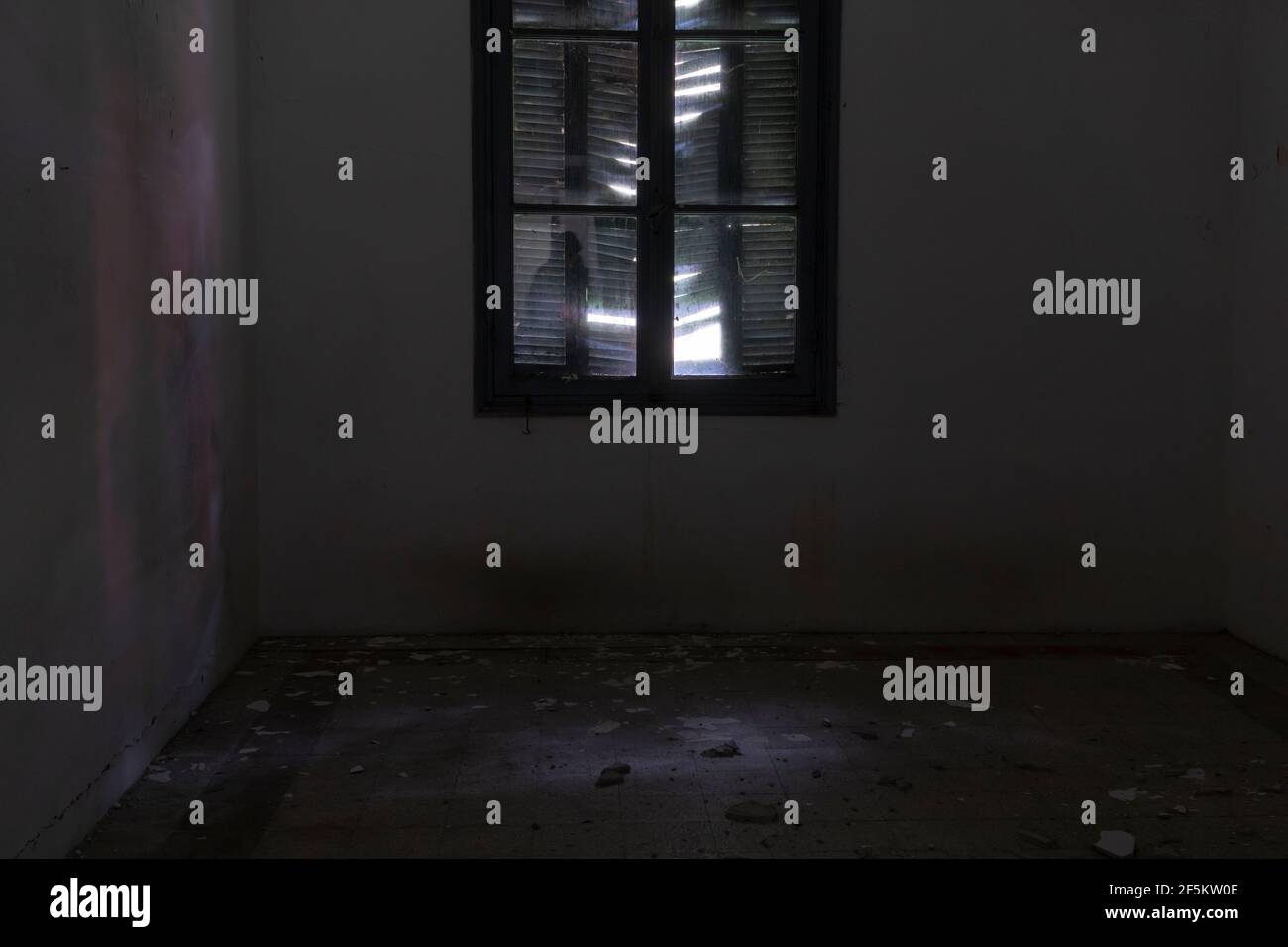 Im Inneren eines verlassenen dunklen Gebäudes kommt nur wenig Licht durch das Fenster Stockfoto