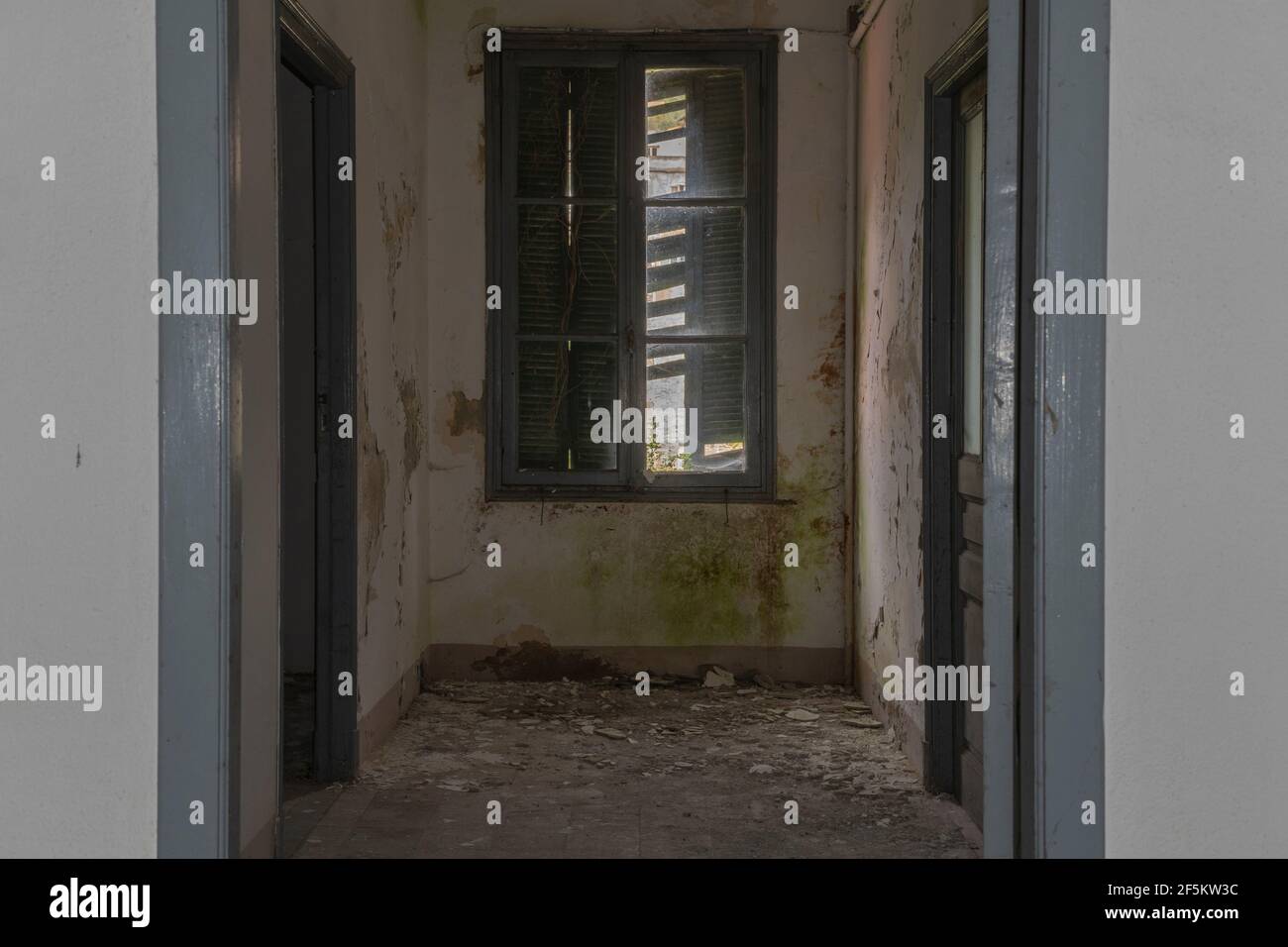 Im Inneren eines verlassenen dunklen Gebäudes kommt nur wenig Licht durch das Fenster Stockfoto
