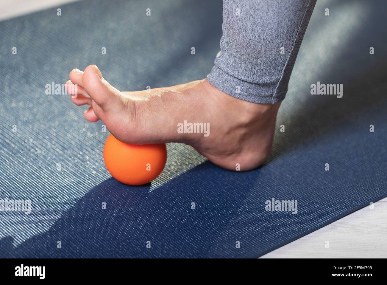 Myofasziale Entspannung der Hyper-beweglichen Muskeln des Fußes, mit einem Massageball auf einer Gymnastikmatte, Nahaufnahme. Konzept zur Vermeidung von Ermüdung des Fußes. Stockfoto