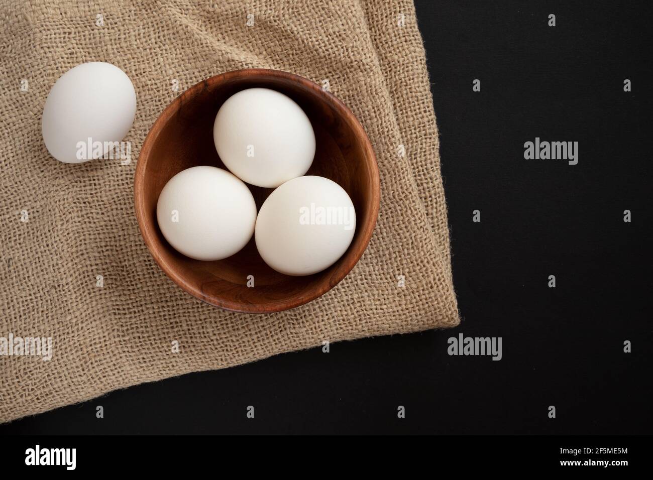 Frische Hühnereier in einem Holzteller auf einem Holztisch Hintergrund. Stockfoto