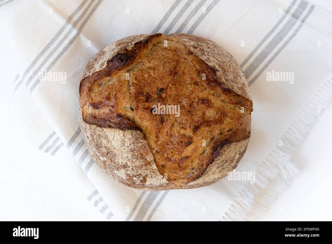 Hausgemachtes Brot. Frisch gebackenes rundes Brot aus Sauerteig mit Leinentuch, Vorderansicht horizontal. Stockfoto