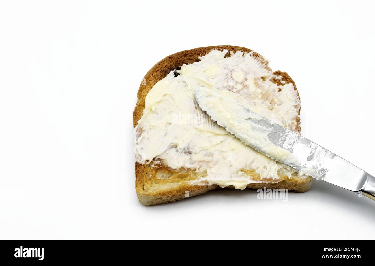 Butter mit einem Messer auf weiß isoliertem Toast verteilen Hintergrund Stockfoto