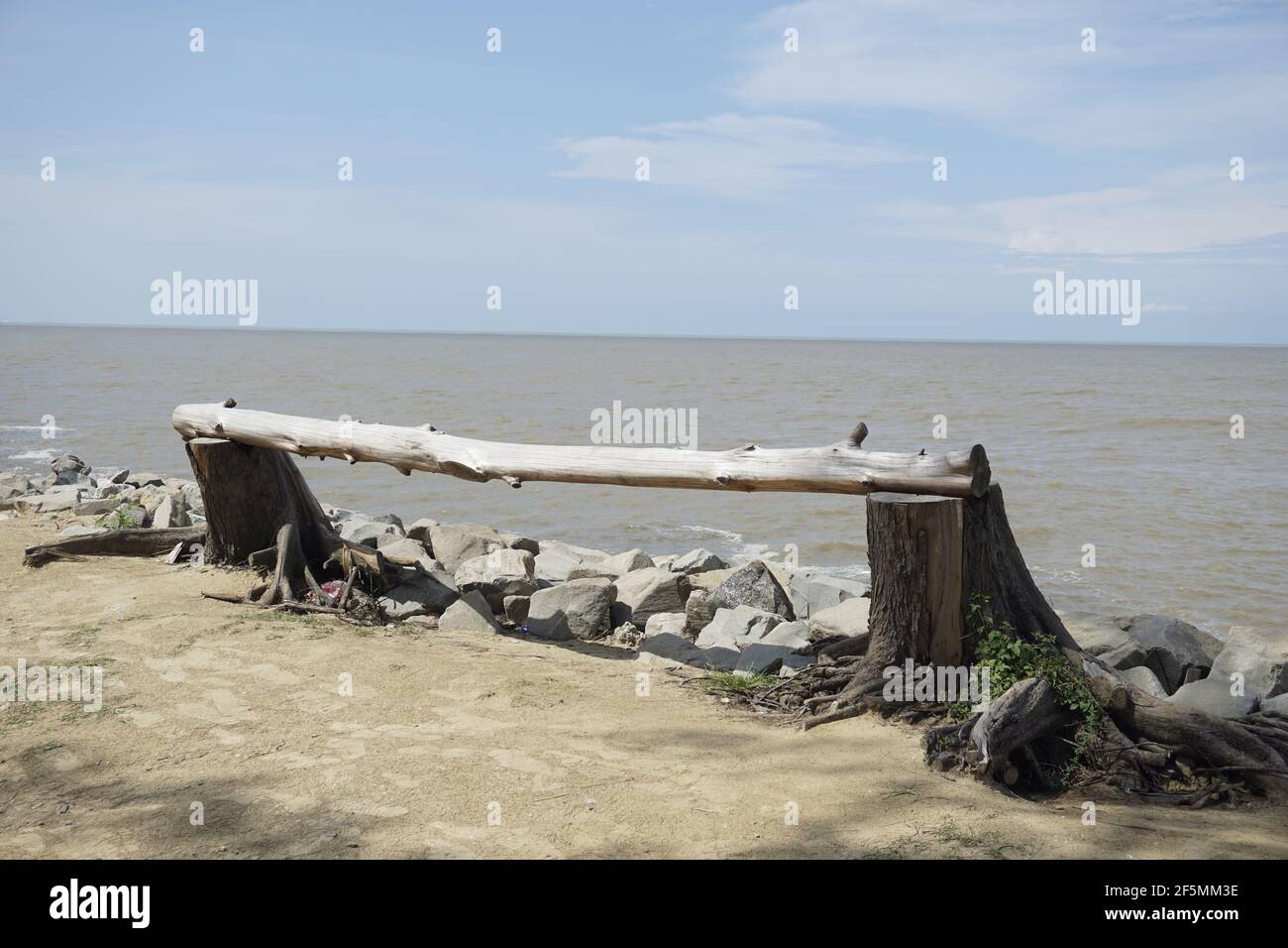 Ein Stück Holz auf zwei Baumstümpfen am Strand am Meer platziert Stockfoto