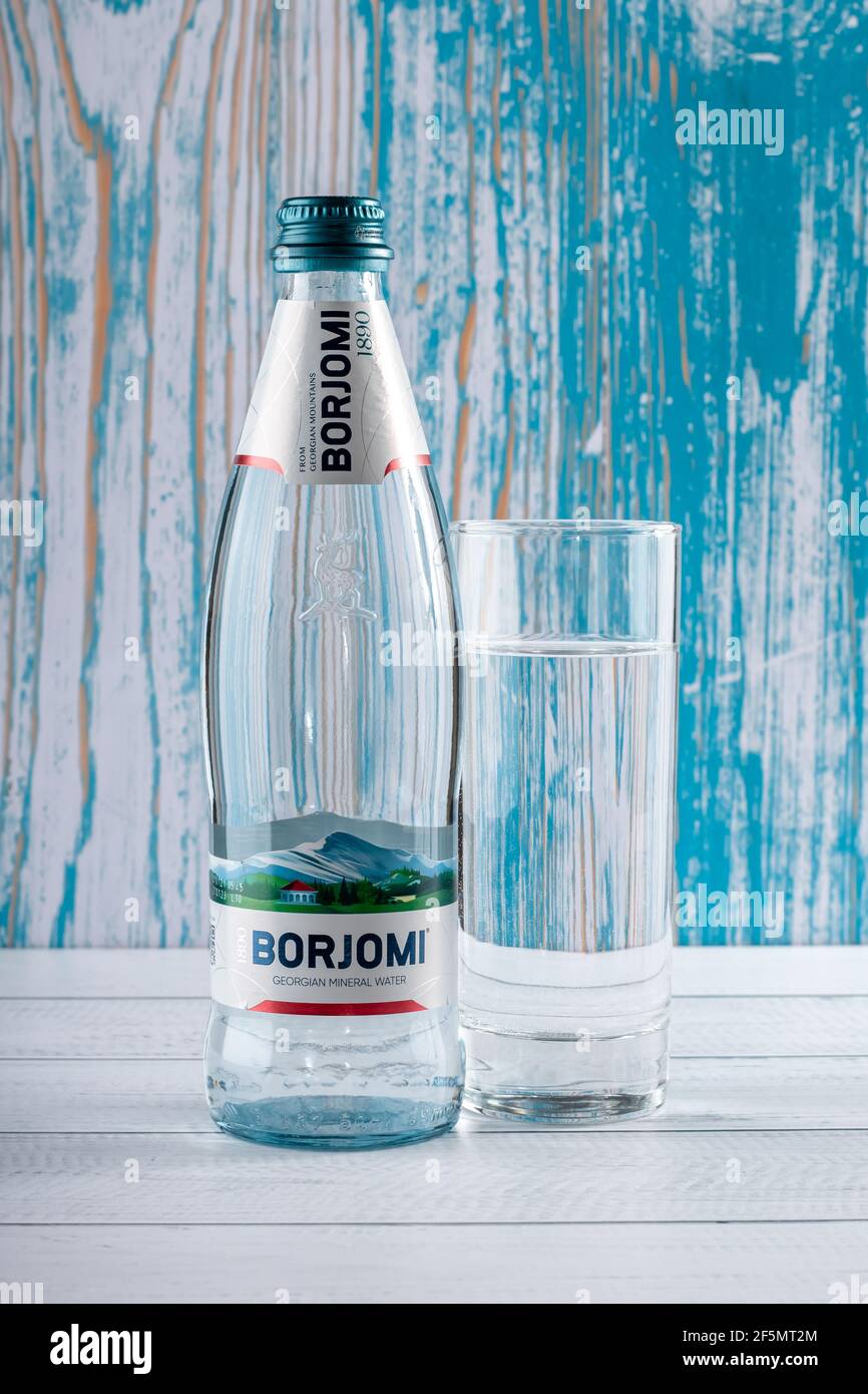 Borjomi Glasflasche, georgisches Mineralwasser auf türkisfarbenem Holz Hintergrund. Gesundes Getränk, das Sodbrennen beseitigt. Logo, Marke des beliebten Unternehmens. Stockfoto
