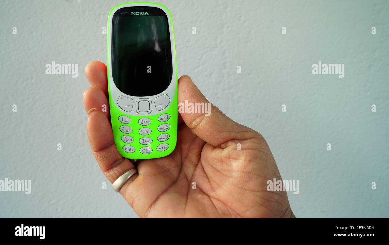 Rajasthan, Indien - 20. März 2021; EIN Mann hält Nokia Tastatur mobile Modell 3310 mit schwarzem Bildschirm isoliert auf weißem Hintergrund. Smartphone-Taste I drücken Stockfoto