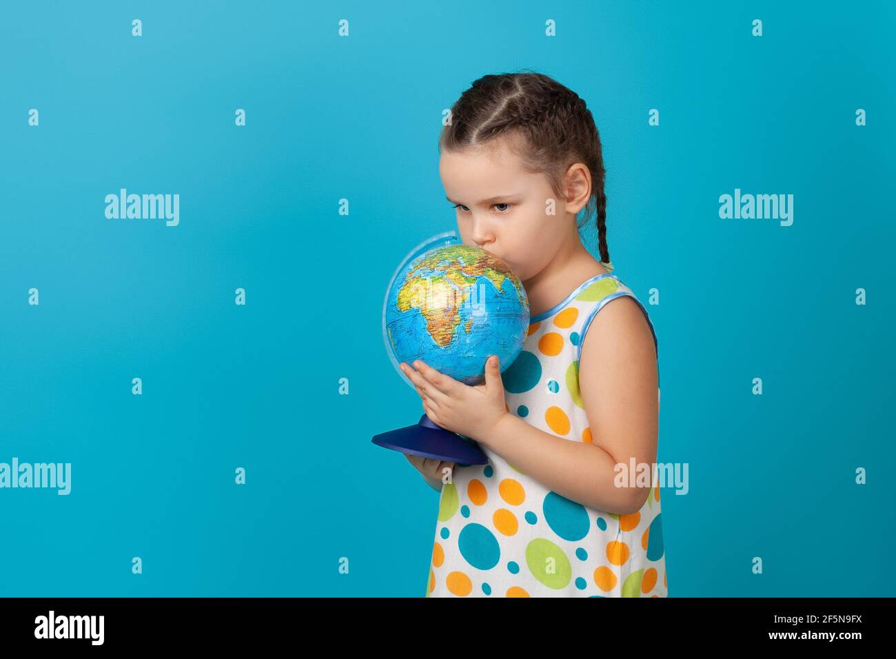 Nahaufnahme Porträt eines traurigen Mädchen in einem weißen Sommerkleid umarmt und küsst einen Globus, Umweltkatastrophe, isoliert auf einem blauen Hintergrund Stockfoto