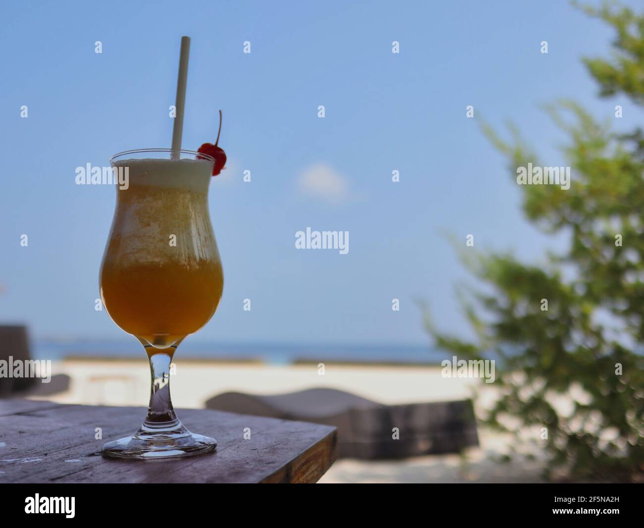 Fruchtiger Cocktail mit Stroh auf Holztisch im Resort auf den Malediven. Alkoholische Getränke am Strand. Stockfoto