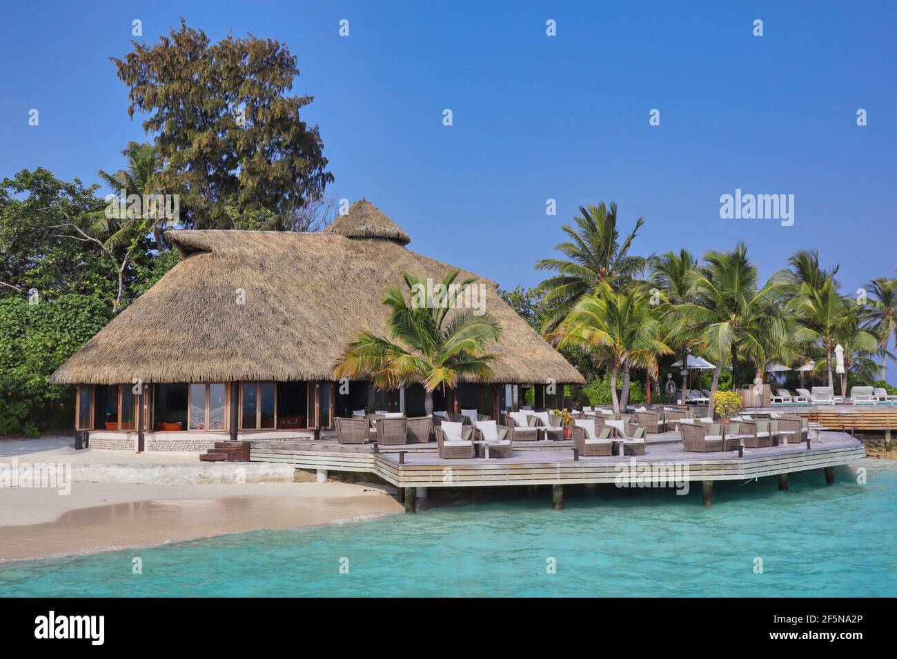 Strohgedeckte Bar mit Stühlen auf den Malediven mit Türkismeer und blauem Himmel. Maledivische Resort Komandoo. Stockfoto