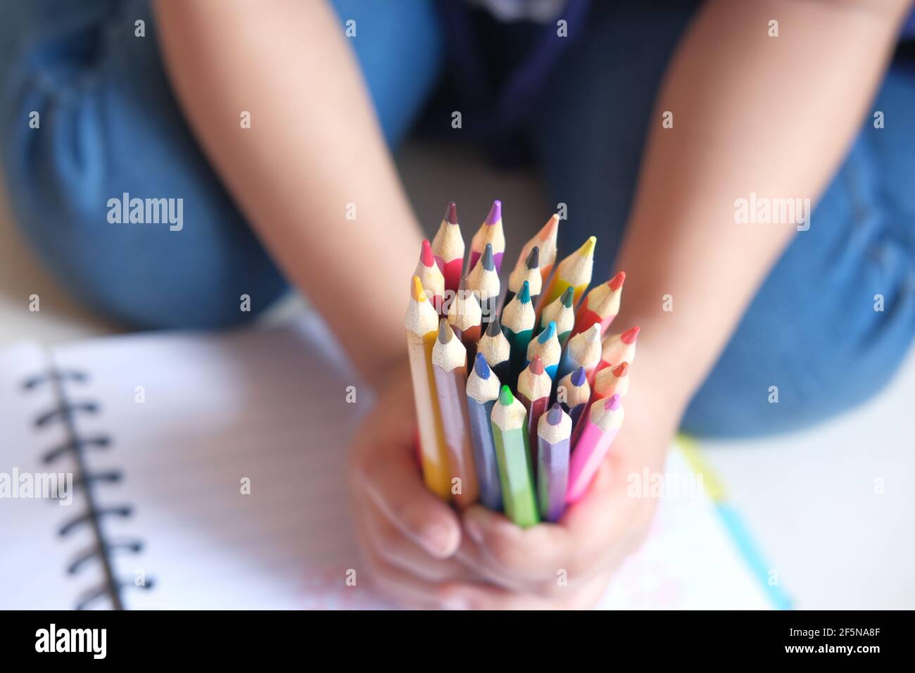 Nahaufnahme einer Kinderhand mit vielen bunten Stiften Stockfoto