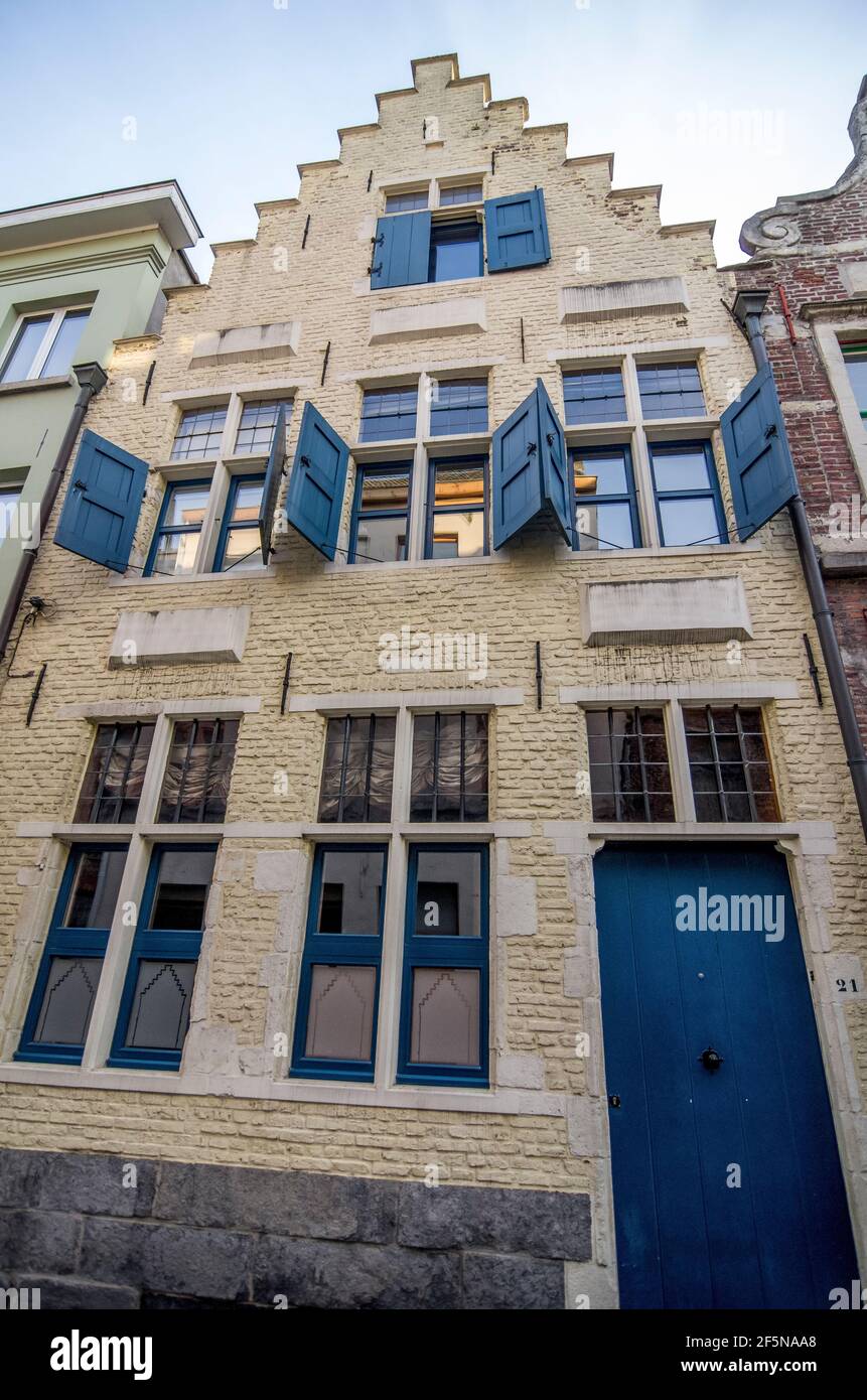 Ein altes gelbes Backsteingebäude mit blauen Fensterläden und Tür im Stadtteil Patershol von Gent, Belgien Stockfoto