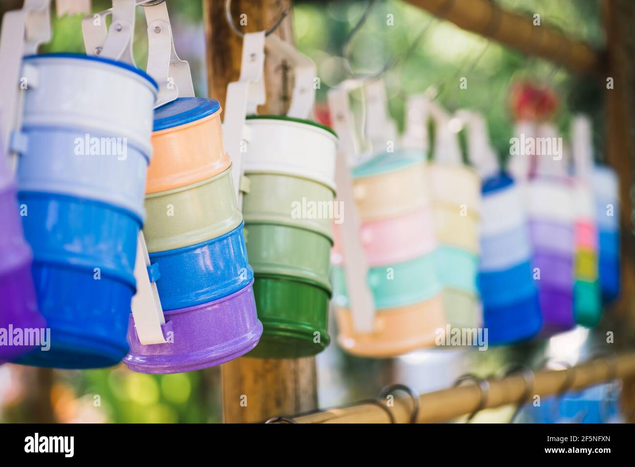 Stillleben mit mehrfarbigen Futterträger oder Tiffin-Träger, der am Holzstab hängt. Selektive Fokus Vintage Retro Thai Stil bunte Tiffin carrie Stockfoto