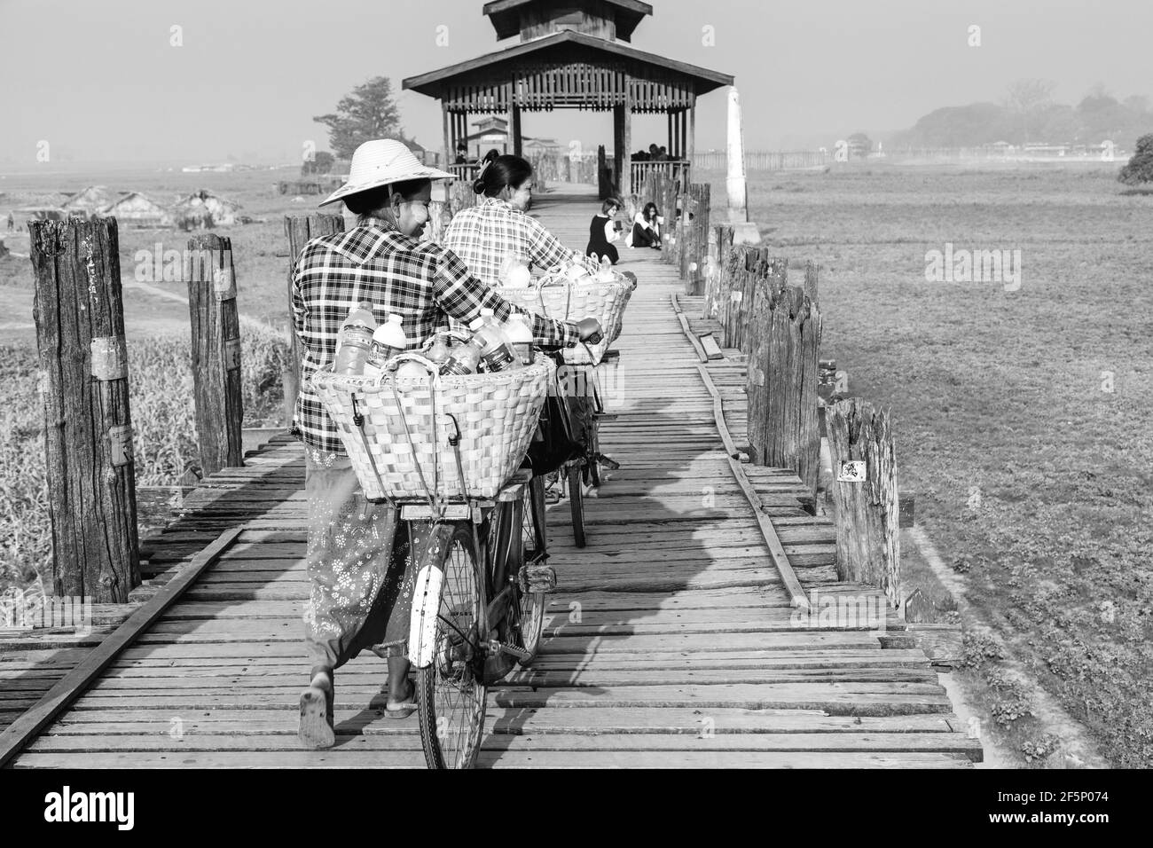 Zwei Frauen mit Fahrrädern über die U-Bein Brücke, Amarapura, Mandalay, Myanmar. Stockfoto