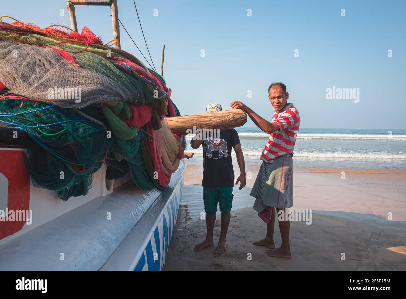 Weligama, Sri Lanka - März 28 2019: Einheimische Fischer aus Sri Lanka bringen ihr traditionelles Fischerboot mit dem Katamaran an den Strand von Weligama, Sri Lanka. Stockfoto