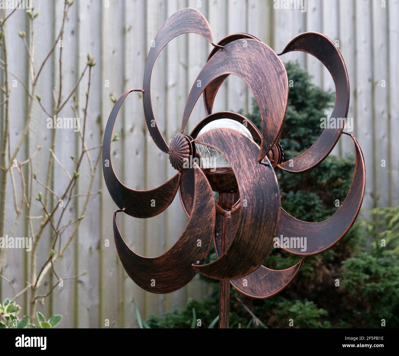 Bronzefarbene Garten verfügen über Solarlicht Doppel Windmühle gegen Holz Zaun Stockfoto
