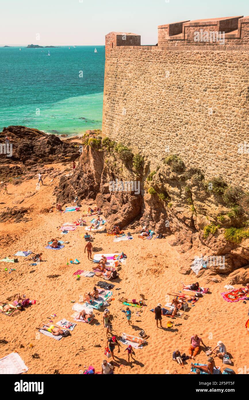 Der Strand und die Menschen Sonnenbaden unter den Stadtmauern, von der mittelalterlichen Festung unter den Stadtmauern in Saint Malo, Frankreich, Britanny Stockfoto