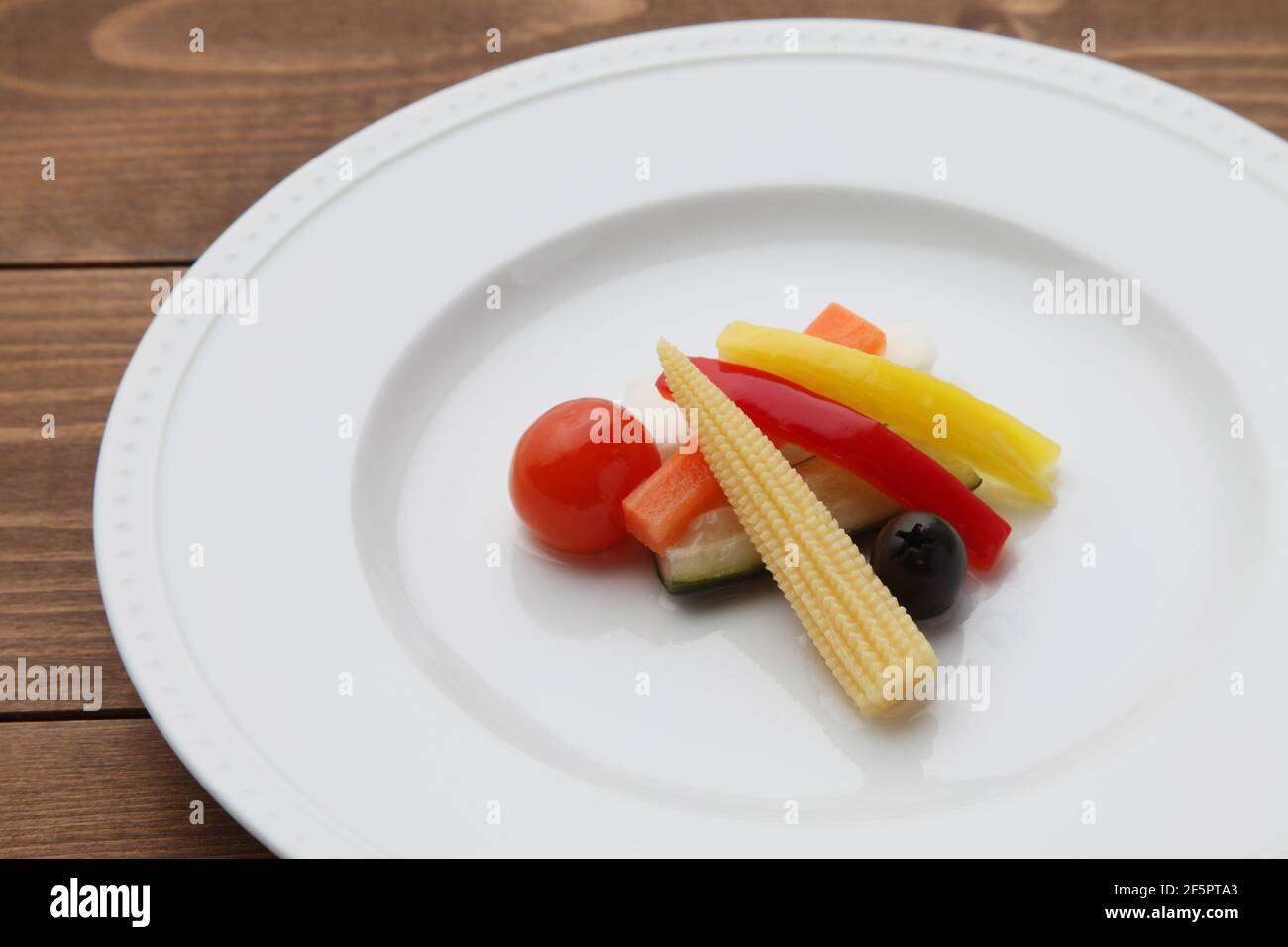 Gurken eingelegter Gemüsesalat auf Teller isoliert auf Holztisch Stockfoto