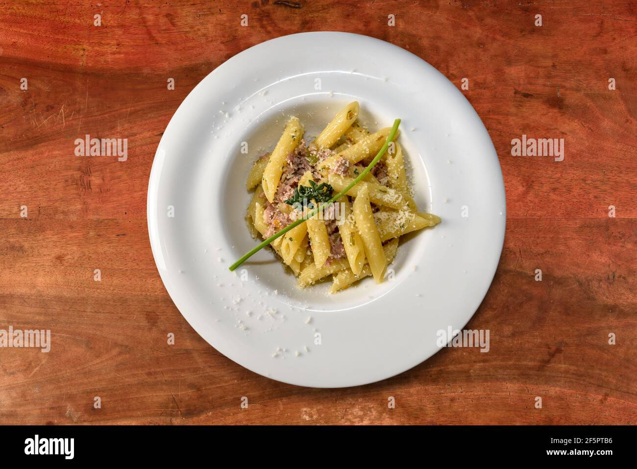 penne Pasta mit Wurst Fleischsoße und Thymian. Macaroni italienische Pasta in weißer Schale auf Holztisch, Draufsicht, flach legen Stockfoto