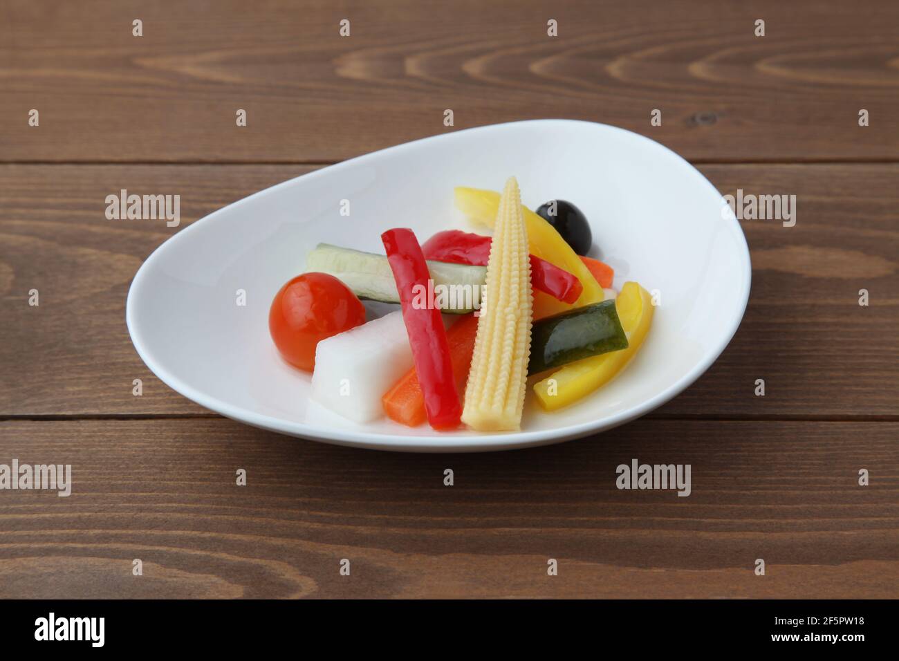 Gurken eingelegter Gemüsesalat auf Teller isoliert auf Holztisch Stockfoto
