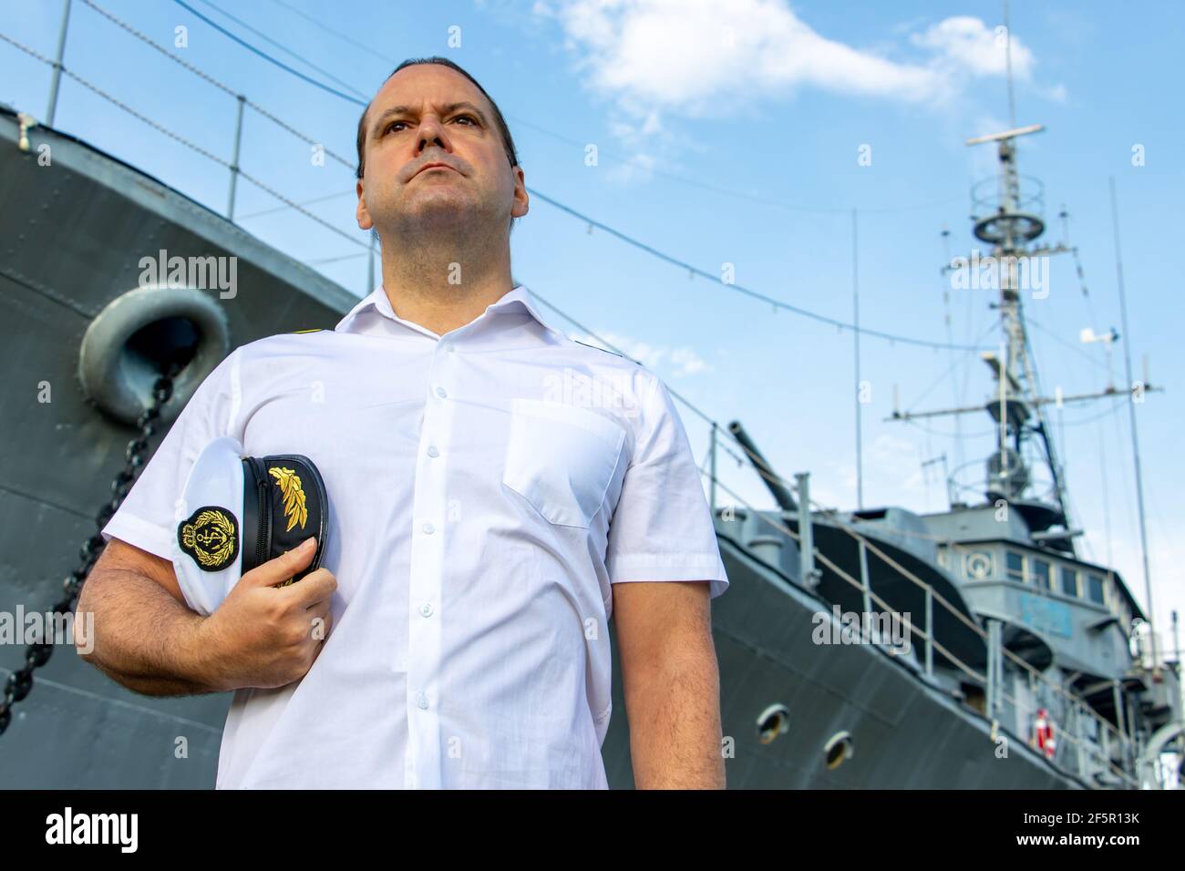 Der Seemann Offizier in weißer Uniform steht neben dem Schlachtschiff. Stockfoto