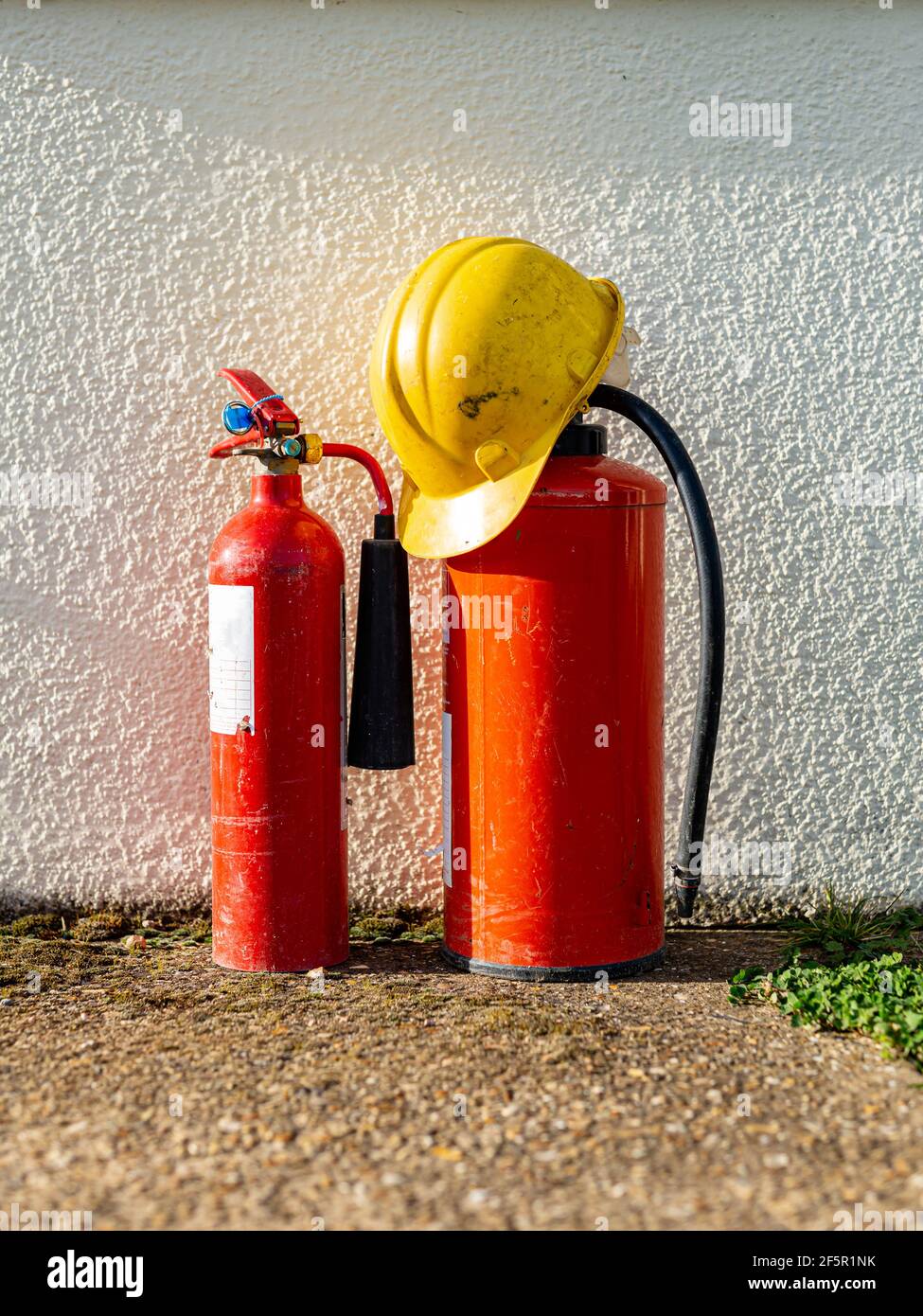 2 Feuerlöscher mit Schutzhelm. Brandschutz, Baustelle, Gebäudekonzept Stockfoto