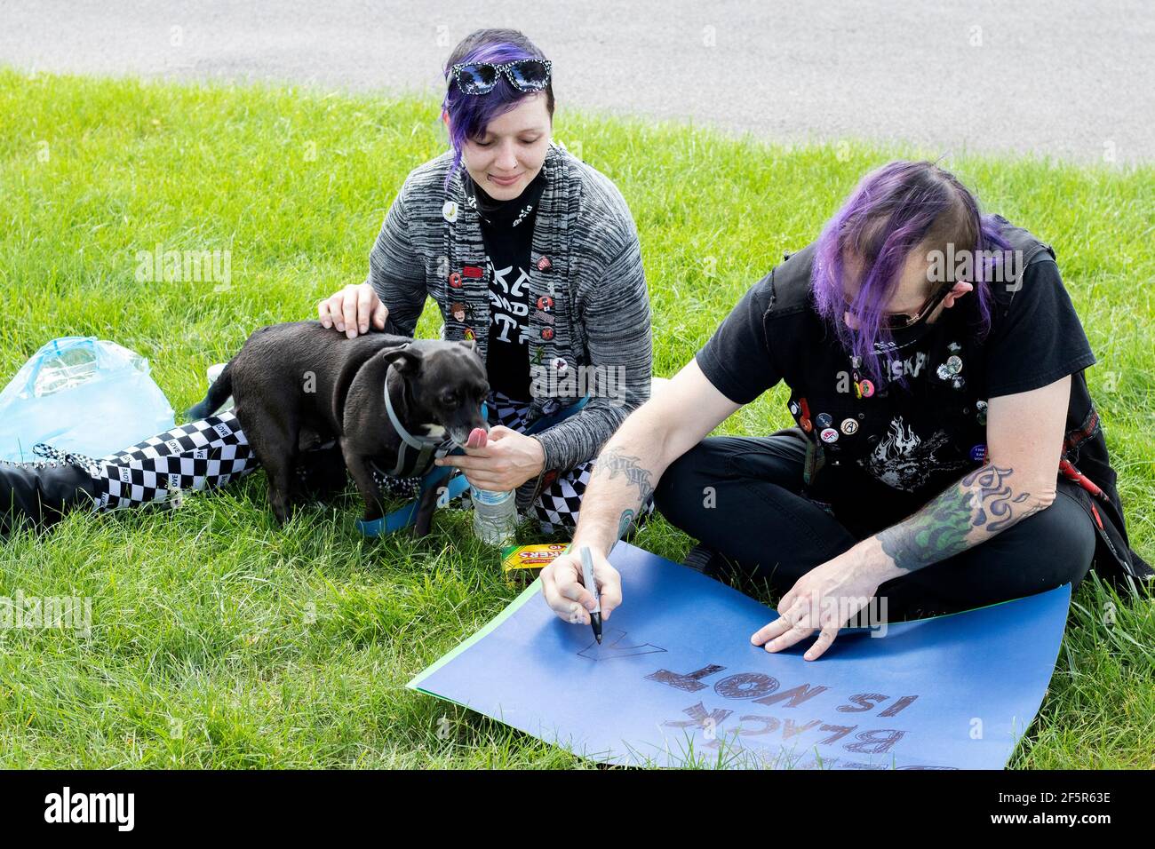 Junge Erwachsene Mann und Frau mit Hund machen Poster an Ein Protest oder eine Kundgebung Stockfoto