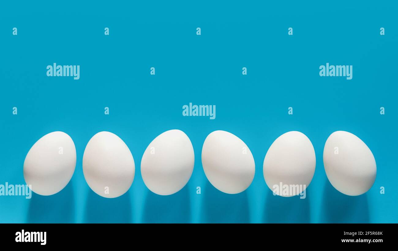 Weiße Eier in einer Reihe auf blauem Hintergrund mit Kopie Platz Stockfoto