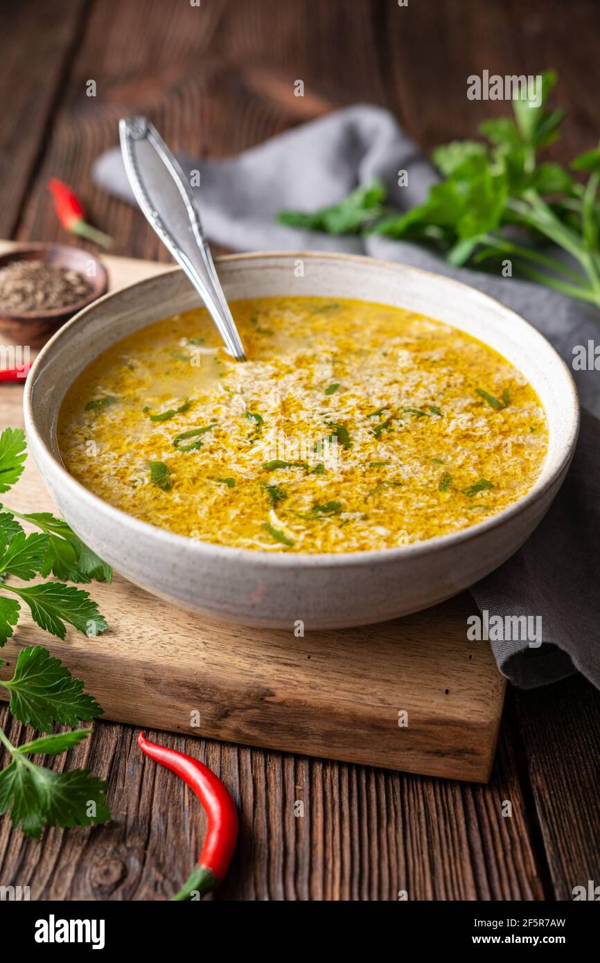 Schnell und einfach würzige Eiertropfensuppe mit Petersilie und Chili auf rustikalem Holzhintergrund Stockfoto