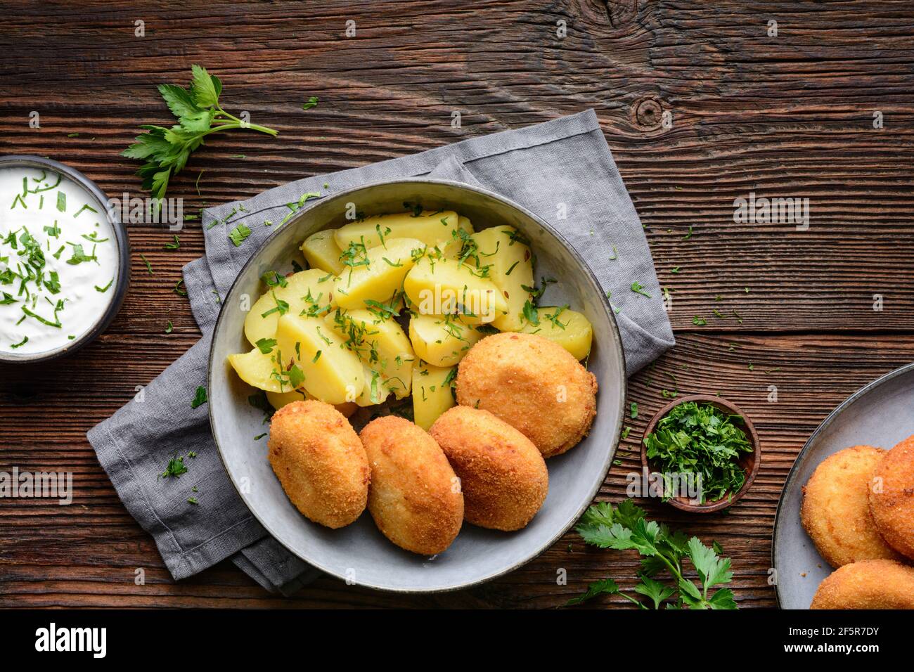 Gebratener Blumenkohl- und Käsebroketten mit gekochten Kartoffeln und sauer Creme Dip auf rustikalem Holzhintergrund Stockfoto