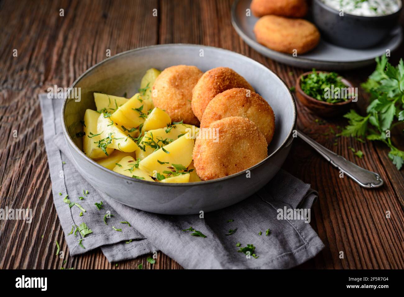 Gebratener Blumenkohl- und Käsebroketten mit gekochten Kartoffeln und sauer Creme Dip auf rustikalem Holzhintergrund Stockfoto