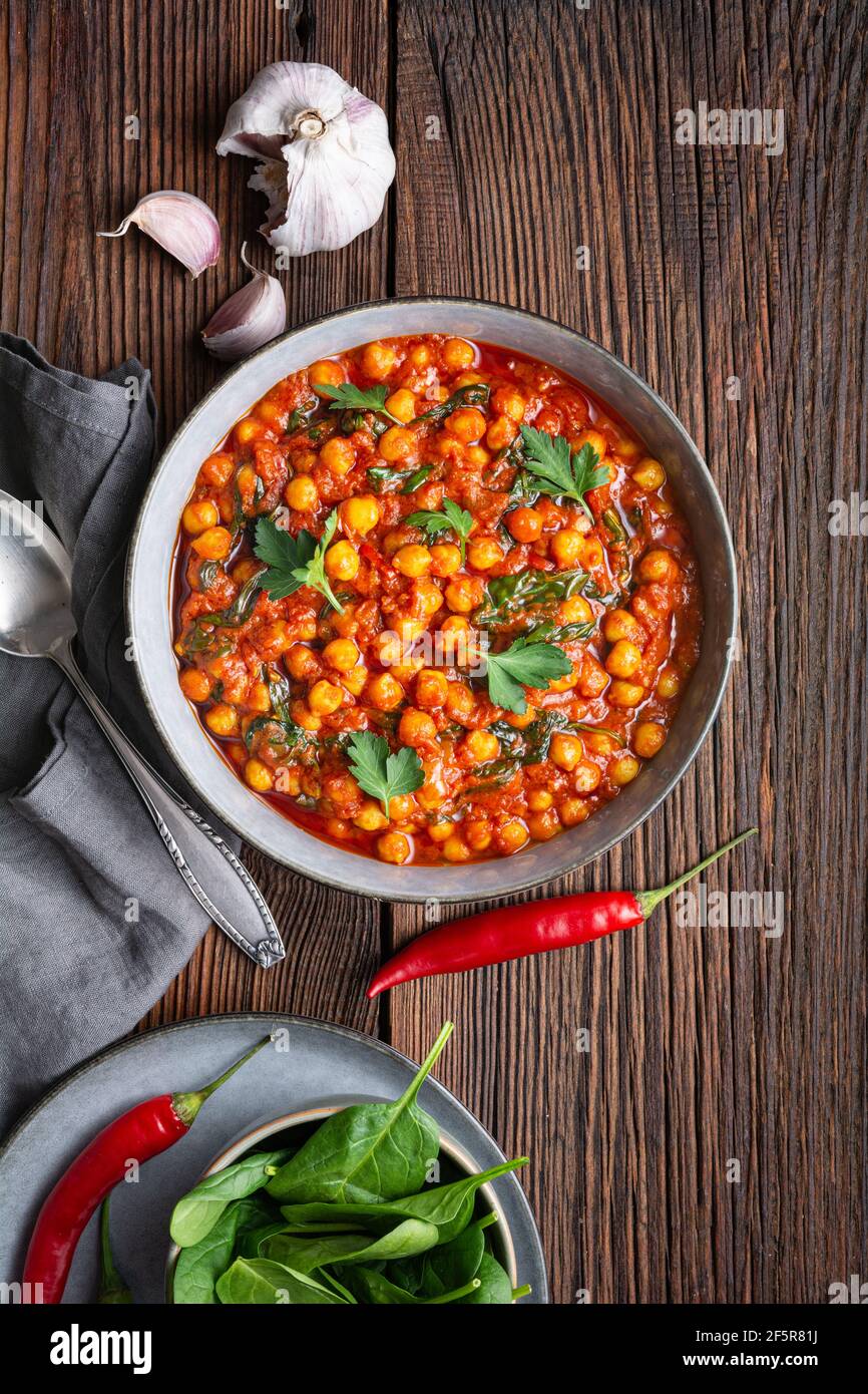 Indische Mahlzeit, würziges Kichererbsencurry mit Spinat in einer Schüssel auf rustikalem Holzhintergrund Stockfoto