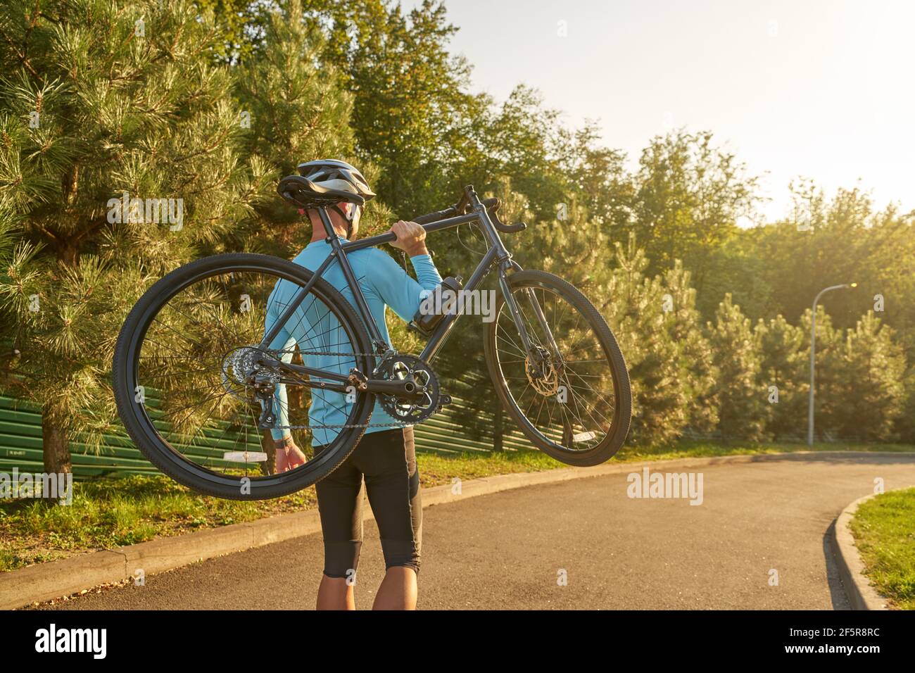 Starker sportlicher Radler in Sportbekleidung und Schutzhelm tragen Sein  Fahrrad nach dem Training im Park bei Sonnenuntergang Stockfotografie -  Alamy