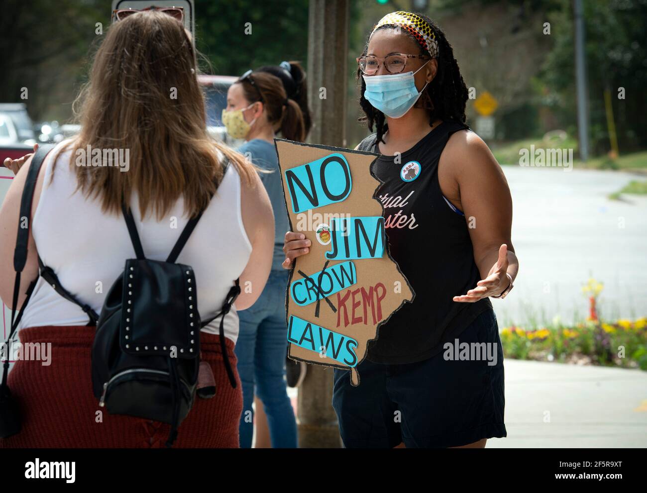 Avondale Estates, GA, USA. März 2021, 27th. Demonstranten versammeln sich an einer belebten Straßenecke, um ihre Opposition zu äußern und den Bewohnern der Gegend Details über eine weitreichende Überarbeitung der staatlichen Wahlgesetze mitzuteilen.Wahlrechtsgruppen sagen, dass das neue Gesetz schwarze Bewohner ansprechen wird, die etwa ein Drittel der Bevölkerung des Staates ausmachen. Der Gesetzentwurf wurde in Gesetz von Georgia Gov unterzeichnet. Brian Kemp, (R) und behandelt eine Vielzahl restriktiverer Maßnahmen, einschließlich der Abschaffung von mobilen Wahlfahrzeugen, die lange Warteschlangen am Wahltag reduzierten, und die kriminalisierte Verteilung von Lebensmitteln oder Wasser an alle, die Schlange stehen Stockfoto