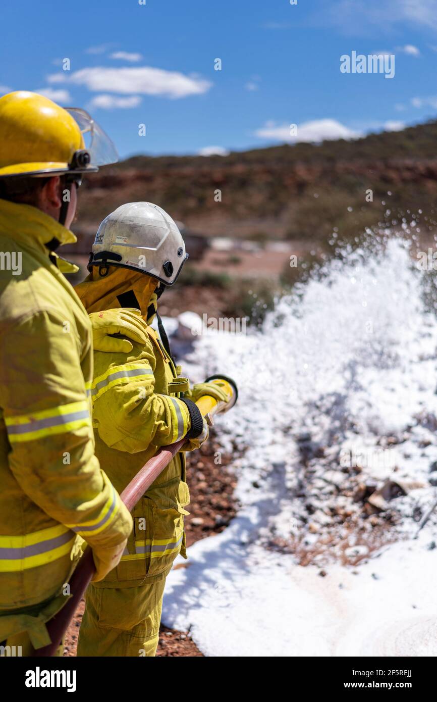 Das Notfallteam der Mine in Schutzkleidung übt das Sprühen von Schaumstoff während der Brandbekämpfung und Rettungsübungen für die Opfer auf dem Brandgelände. Stockfoto