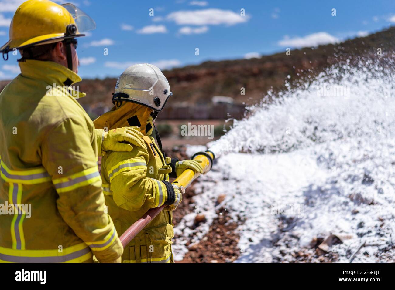 Das Notfallteam der Mine in Schutzkleidung übt das Sprühen von Schaumstoff während der Brandbekämpfung und Rettungsübungen für die Opfer auf dem Brandgelände. Stockfoto